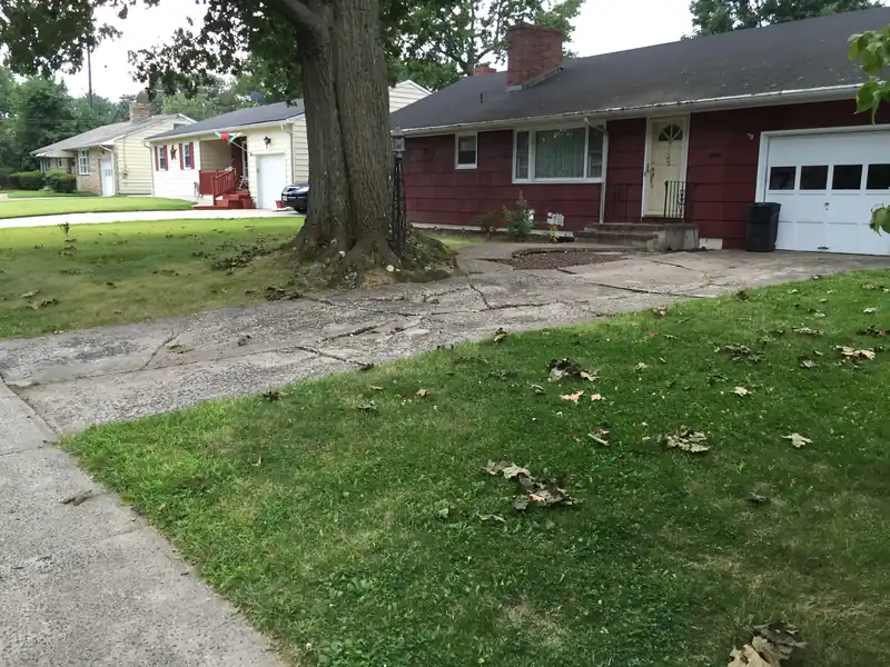 Long concrete driveway beside a lawn leading to a brick house