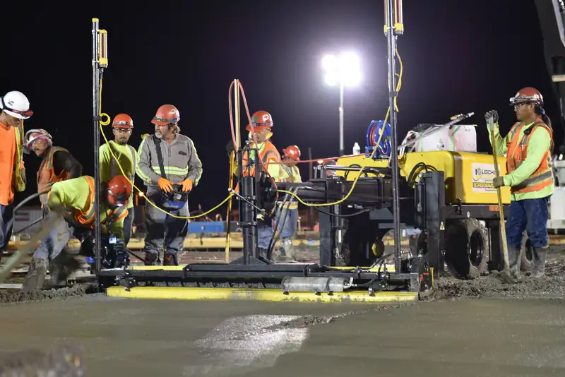 Flatwork crew finishing a large slab under lights at night