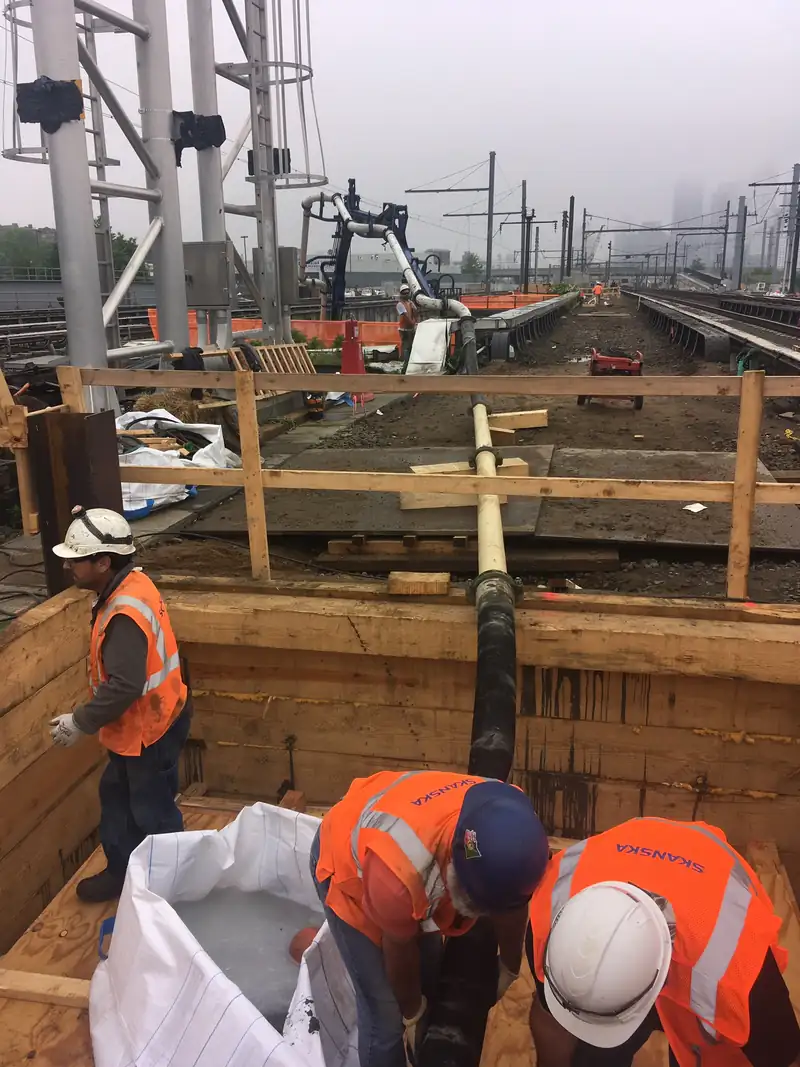 Worker guiding a concrete pump hose while placing a slab